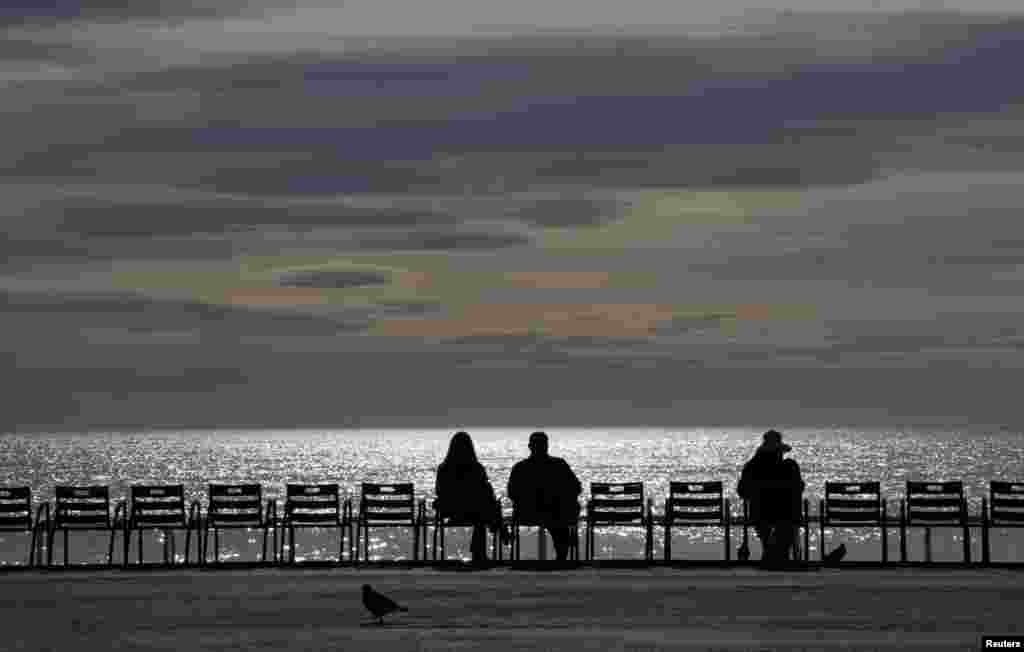 People enjoy a sunny autumn day on the Promenade des Anglais in Nice, France.