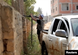 A member of the Libyan internationally recognized government forces fires at eastern forces in Ain Zara, Tripoli, Libya, April 25, 2019.