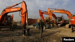 A man walks next to machinery parked at the Omid Gardizi construction company in Kabul, Afghanistan, Nov. 30, 2015.