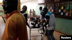 People escort a wounded civilian at the community hospital in Bangui, Feb. 19, 2014.
