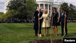 Brigitte Macron holds the shovel used by U.S. President Donald Trump after a tree planting as and first lady Melania Trump and French President Emmanuel Macron stand on the South Lawn of the White House in Washington, April 23, 2018.