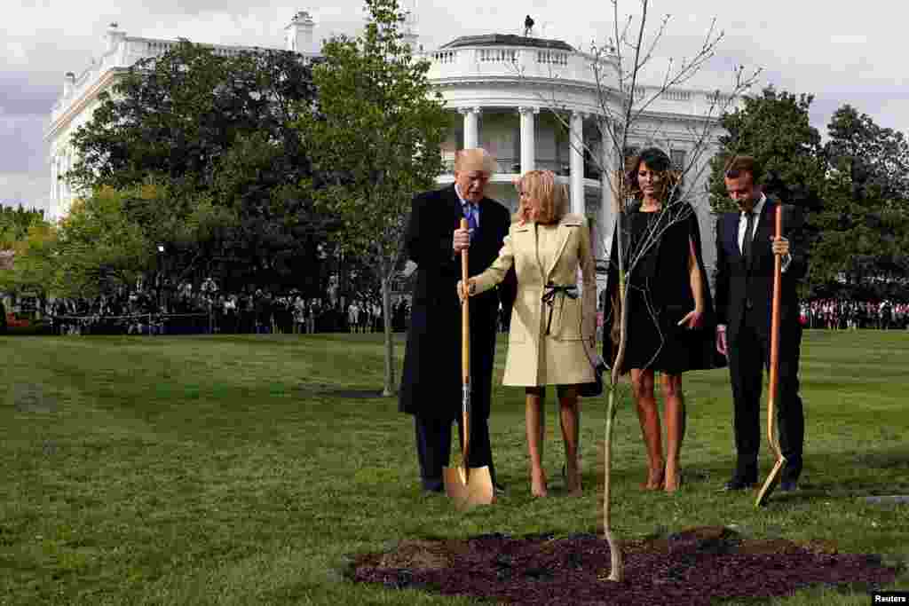 Brigitte Macron holds the shovel used by U.S. President Donald Trump after a tree planting as and first lady Melania Trump and French President Emmanuel Macron stand on the South Lawn of the White House in Washington, April 23, 2018.