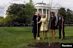 Brigitte Macron holds the shovel used by U.S. President Donald Trump after a tree planting and first lady Melania Trump and French President Emmanuel Macron stand on the South Lawn of the White House in Washington, April 23, 2018.