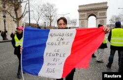 A protester holds the French flag on the Champs-Elysees near the Arc de Triomphe during a demonstration by the "yellow vest" movement in Paris, March 9, 2019. The writing on the flag reads: "Gauls are angry. The people are on the street."