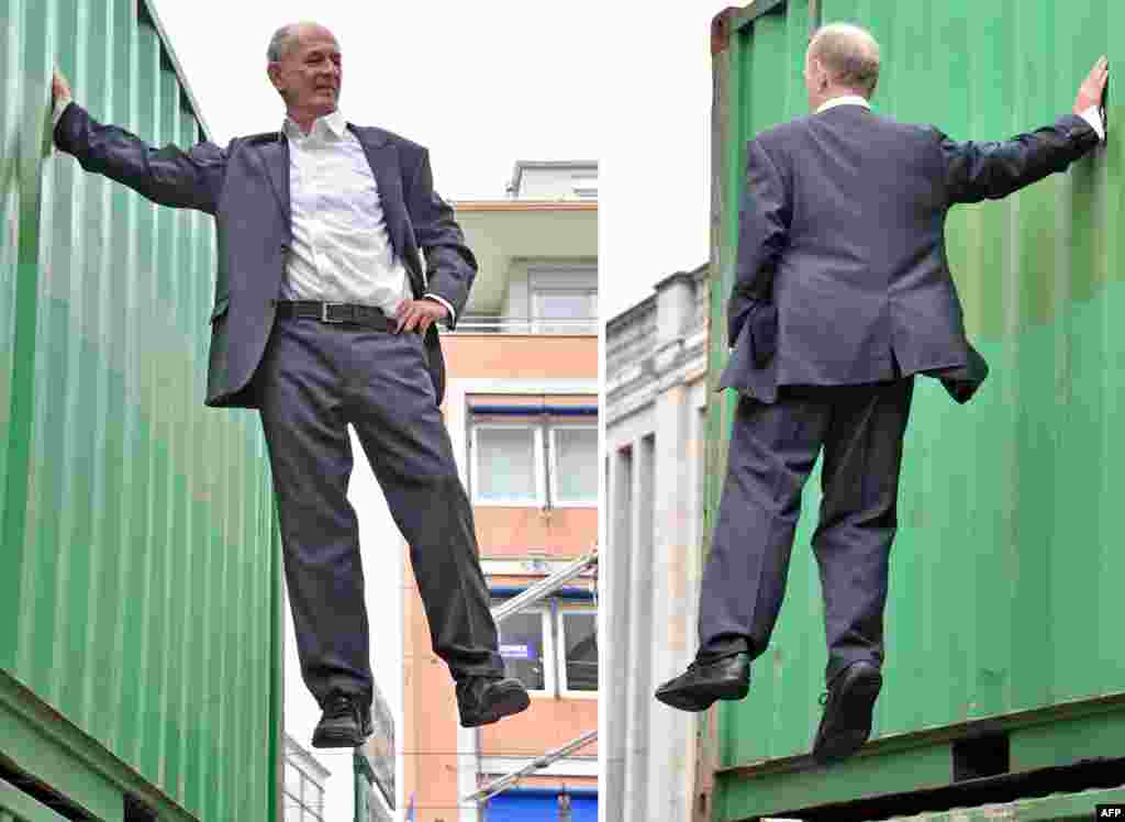 A combination of two pictures shows German artist Johan Lorbeer clinging at a container during the performance "Tarzan/Standbein" (Tarzan/supporting leg) during the open air exhibition "The city is the star, Art at the construction site" in Karlsruhe, southwestern Germany, Aug. 1, 2015.