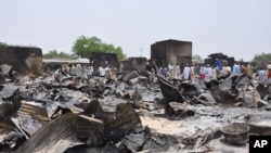 Des gens contemplent les dégats de l'explosion d'une bombe à Gambaru, dans l'état de Borno, le 11 mai 2014.