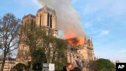 Notre Dame cathedral is burning in Paris, April 15, 2019. Massive plumes of yellow brown smoke is filling the air above Notre Dame Cathedral and ash is falling on tourists and others around the island that marks the center of Paris. 