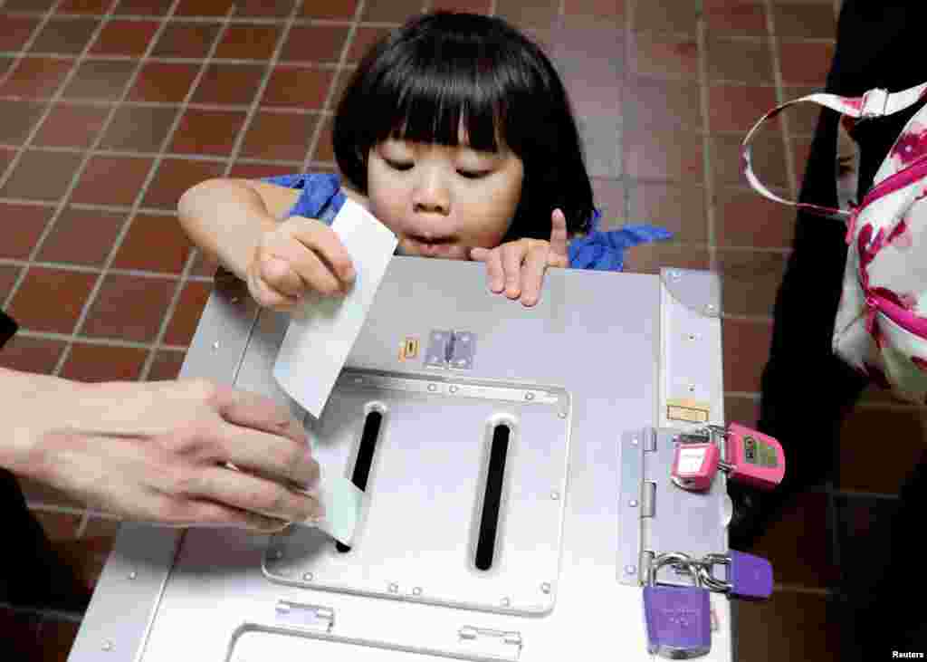 일본 중의원 총선거가 열린 도쿄의 한 투표소에서 어린 소녀가 아버지의 투표 용지를 투표함에 넣고 있다.