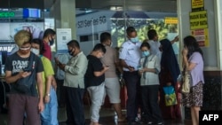 Orang-orang memindai kode QR untuk menunjukkan pelacakan kontrak tentang keberadaan mereka, sebelum memasuki pusat perbelanjaan di Surabaya pada 10 Agustus 2021, saat pemerintah menerapkan bentuk penguncian yang lebih ketat. (Foto: AFP/Juni Kriswanto)