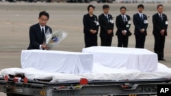 Japanese Foreign Minister Fumio Kishida, left, lays flowers on the coffins of the victims who were killed in the last weekend's attack on a restaurant in Bangladeshi capital Dhaka, at Haneda Airport in Tokyo, Tuesday, July 5, 2016.
