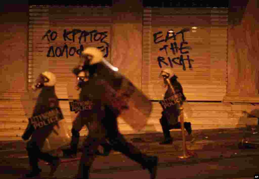 Riot police chase protesters in front of a hotel during a protest in Athens after a Greek retiree shot himself, April 4, 2012. (AP)