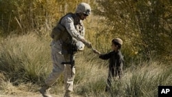 U.S. Marine 1st Sergeant Christopher Adams of 2nd Battalion 2 Marines of 2nd Marine Expeditionary Brigade gives an Afghan child a pen in Mian Poshteh in Helmand Province. 26 Nov 2009
