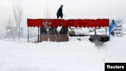 An Afghan man removes snow from his shop on the outskirts of Kabul, Feb. 5, 2017.