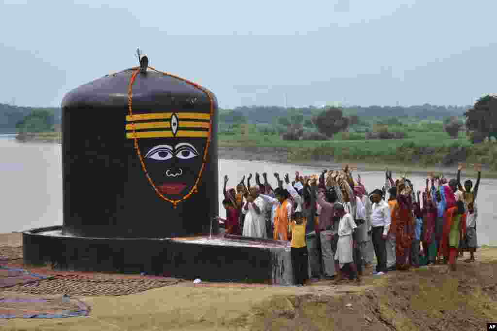 Devotees raise their hands and chant religious slogans as they worship newly installed 'lingam', representing Hindu deity Shiva on the banks of the river Yamuna in Agra, India.