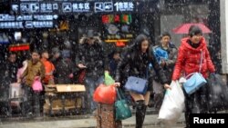 People carrying luggages leave a railway station in snow in Wuhan, Hubei province, Jan. 31, 2016. 