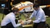 Georgia Tech postdoctoral fellow Michael Ward, left, and DARPA’s Ashish Bagai demonstrate how helicopter landing gear respond to obstacles in the landing zone, represented here by concrete blocks. Each leg adjusts independently so the helicopter stays level,