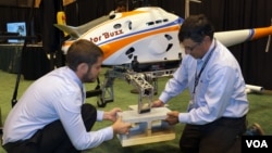 Georgia Tech postdoctoral fellow Michael Ward, left, and DARPA’s Ashish Bagai demonstrate how helicopter landing gear respond to obstacles in the landing zone, represented here by concrete blocks. Each leg adjusts independently so the helicopter stays level,