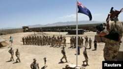 FILE - Australian and British troops stand at attention during an ANZAC day ceremony at Camp Armadillo, in Helmand Province.