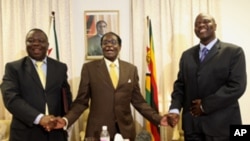 President Robert Mugabe, centre, shares a light moment with Morgan Tsvangirai, left, Zimbabwe's Prime Minister and his Deputy, Arthur Mutambara after giving their end of year message to the nation, at Zimbabwe House in Harare, Wednesday, Dec. 23, 2009