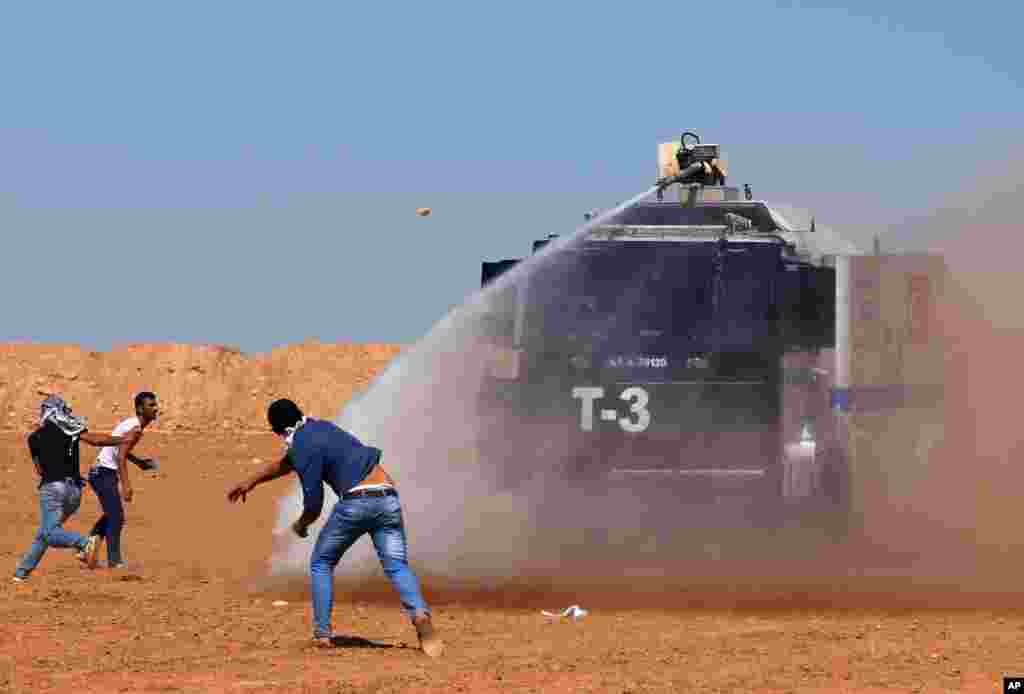 Turkish security forces use teargas and water cannons to disperse protesting local people as several hundred Syrian refugees wait at the border in Suruc, Turkey, Sept. 21, 2014.