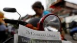 FILE - A woman buys the final issue of The Cambodia Daily newspaper at a store along a street in Phnom Penh, Cambodia, Sept. 4, 2017. 