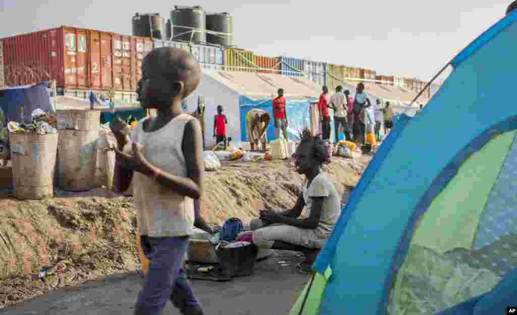 A young displaced girl washes clothes alongside a row of tents in the United Nations compound in Juba,