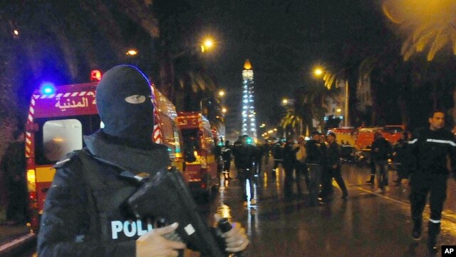 Un policía en Túnez bloquea el ingreso de la prensa al lugar donde una explosión en un autobús que llevaba miembros de la guardia presidencial dejó al menos 12 muertos. Nov. 24 de 2015.