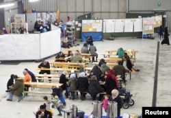 Migrants sit in a canteen in a refugee camp in Celle, Lower-Saxony, Germany, Oct. 15, 2015.