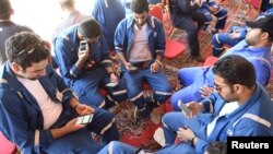 Kuwait Oil and Petrochemical Industries Union workers sit with their cellphones on the first day of an official strike over public sector pay reforms, in Ahmadi, Kuwait, April 17, 2016. 