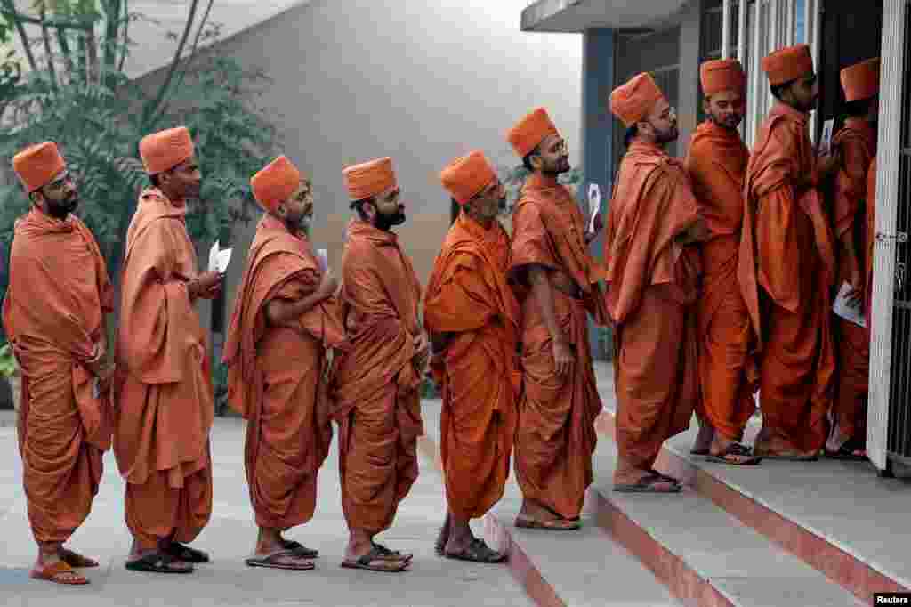 Hindu saints stand in a queue to casts their votes at a polling station during the last phase of Gujarat state assembly election on the outskirts of Ahmedabad, India.