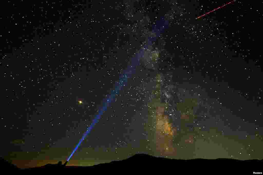 A man points his light at the Milky Way during the peak of the Perseid meteor shower at Mavrovo national park in Macedonia, Aug. 12, 2018.