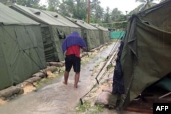 FILE - A man walking between tents at Australia's regional processing centre on Manus Island, in Papua New Guinea.