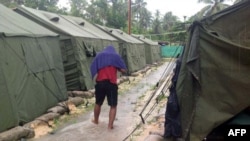 Một người xin tị nạn đi bộ giữa các căn lều tại trung tâm tạm giam của Australia trên đảo Manus, Papua New Guinea.