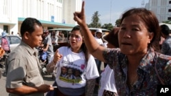 A security guard, left, talks with supporters as he keeps supporters from reaching the Phnom Penh Municipality Court during a gathering to call for the release of anti-government protesters who were arrested in a police crackdown, in Phnom Penh, Cambodia, Wednesday, May 21, 2014. Nearly two dozen of Cambodia's anti-government protesters were arrested earlier this year in connection with social unrest. (AP Photo/Heng Sinith)