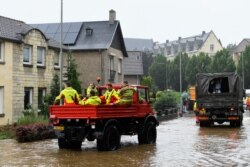 Penjaga pantai duduk di dalam kendaraan di jalanan yang tergenang banjir, menyusul hujan deras di Valkenburg, Belanda, 15 Juli 2021. (REUTERS/Piroschka Van De Wouw)