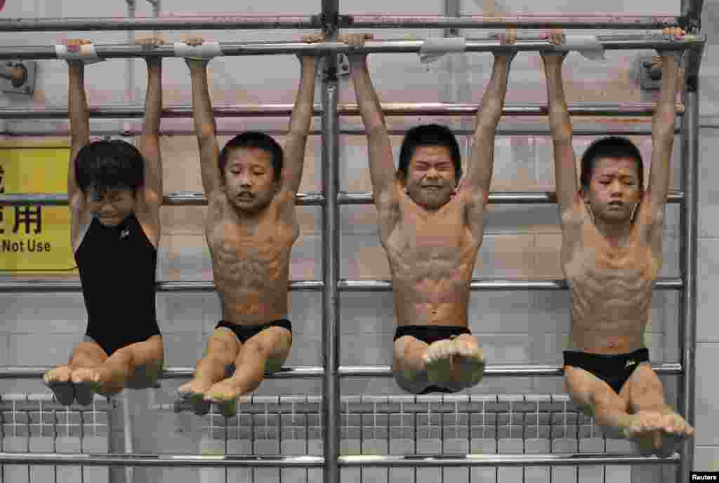 Young divers hang from a steel bar during a training session at a sports school in Hefei, Anhui province, China, August 23, 2014.