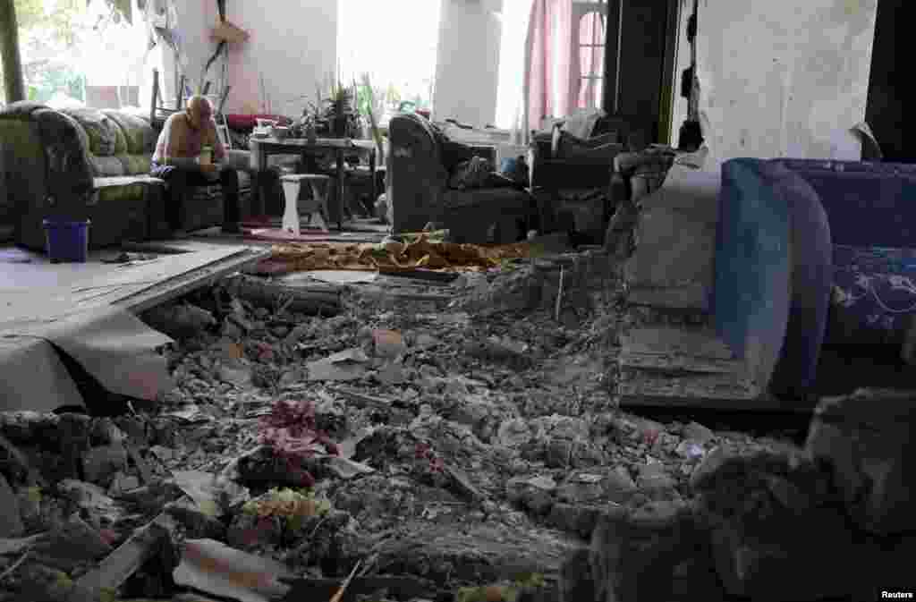 A local resident sits amidst debris at his damaged house, which according to locals was hit by recent shelling in Donetsk, Ukraine, June 22, 2015.