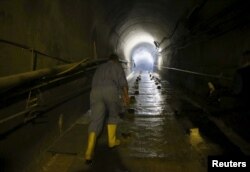 FILE - A laborer walks as he works at strengthening the Mosul Dam at the dam's tunnel in northern Iraq, April 18, 2016.