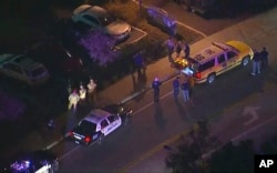 In this image made from aerial video, police vehicles line a road in the vicinity of a shooting in Thousand Oaks, California, early Nov. 8, 2018. Authorities say there were multiple injuries, including one officer, after a man opened fire in Southern California.