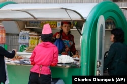 A vendor sells food and drinks out of a kiosk in Pyongyang, North Korea.