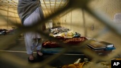 FILE - Afghan detainees are through mesh wire fence inside the Parwan detention facility near Bagram Air Field in Afghanistan.