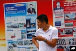 2018年8月22日，北京地铁站外的政府宣传广告牌宣传中国国家主席习近平和中国的经济成就，一名男子站在旁边。