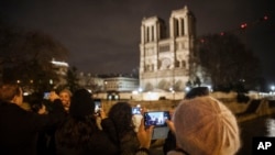 Tourists and visitors take pictures of Notre Dame cathedral in Paris, Monday, Dec. 23, 2019. (AP Photo/Kamil Zihnioglu)
