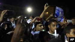 FILE - Sudanese anti-government protesters use their smart phones to film and photograph a demonstration in Khartoum, Sudan.