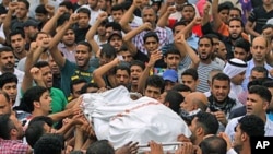 Mourners chant anti-government slogans as they carry the body of Ali Isa Saqer, 31, to be washed for burial in his village of Sehla, Bahrain, April 10, 2011, after he died in police custody in the past week