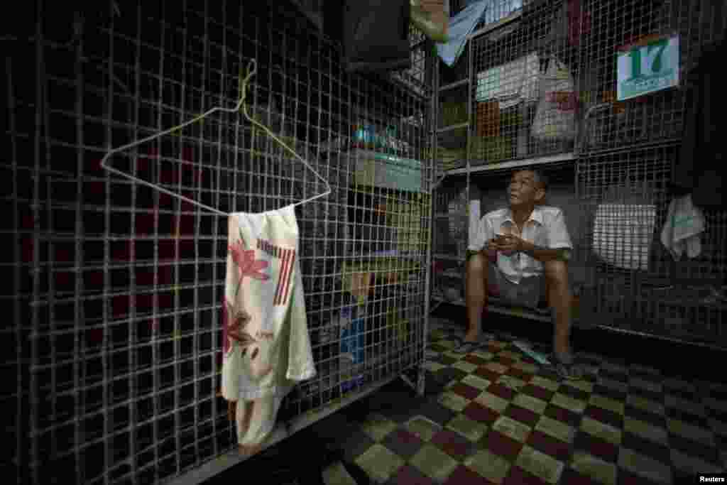 Kong Siu-kau waits for dinner in Hong Kong&#39;s Tai Kok Tsui district, July 16, 2008. As soaring property prices forced rents higher, thousands of Hong Kong residents moved into &quot;cage homes,&quot; 15-square-foot wire mesh cubicles usually crammed eight in a room.