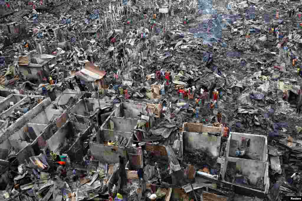 Slum dwellers search for their belongings from ashes after fire broke out on their shelters in Dhaka, Bangladesh, Aug. 17, 2019.