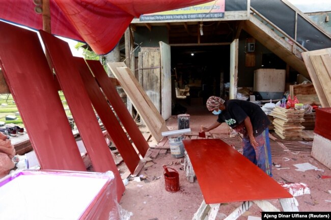 Pembuat peti mati menyiapkan papan untuk peti mati yang dipesan untuk korban COVID-19 di bengkel di dalam kompleks pemakaman di Jakarta, 29 Juni 2021. (Foto: REUTERS/Ajeng Dinar Ulfiana)