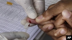 A patient undergoes a pin prick blood test inside a mobile healthcare clinic parked in downtown Johannesburg, 29 Nov 2010