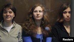 Members of the female punk band "Pussy Riot" (L-R) Yekaterina Samutsevich, Maria Alyokhina and Nadezhda Tolokonnikova sit in a glass-walled cage before a court hearing in Moscow October 10, 2012. 